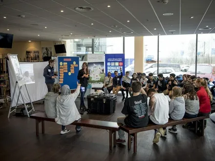 Schulklasse sitzt in einem Halbkreis bei einem Workshop mit Pinnwänden und Projektor unter dem Motto „Schalke macht Schule“.