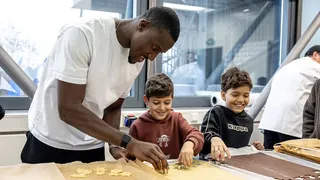 Bryan Lasme backt Plätzchen mit Kindern der Regenbogenschule