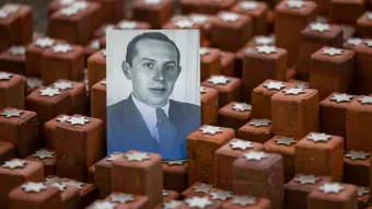 Schwarz-weißes Porträt von Ernst Alexander, eingefügt in ein Mahnmal aus rotbraunen Backsteinen mit silbernen Davidsternen zum Gedenken an die Opfer der Schoah
