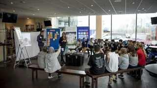 Schulklasse sitzt in einem Halbkreis bei einem Workshop mit Pinnwänden und Projektor unter dem Motto „Schalke macht Schule“.