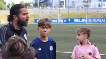 Ein Trainer spricht mit den Kindern und sie schauen konzentriert zum ihm.