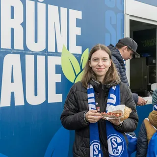 Fan mit veganer Currywurst vor der Grünen Kaue.