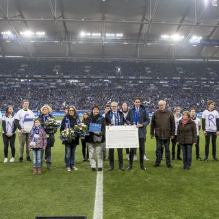 Ehrung des Grillo-Gymnasiums in der Veltins-Arena mit Schülern, Blumen und Urkunde vor vollen Tribünen.