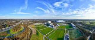Das Bild zeigt das grüne Vereinsgelände des S04. Im Hintergrund ist die VELTINS-Arena zu sehen.